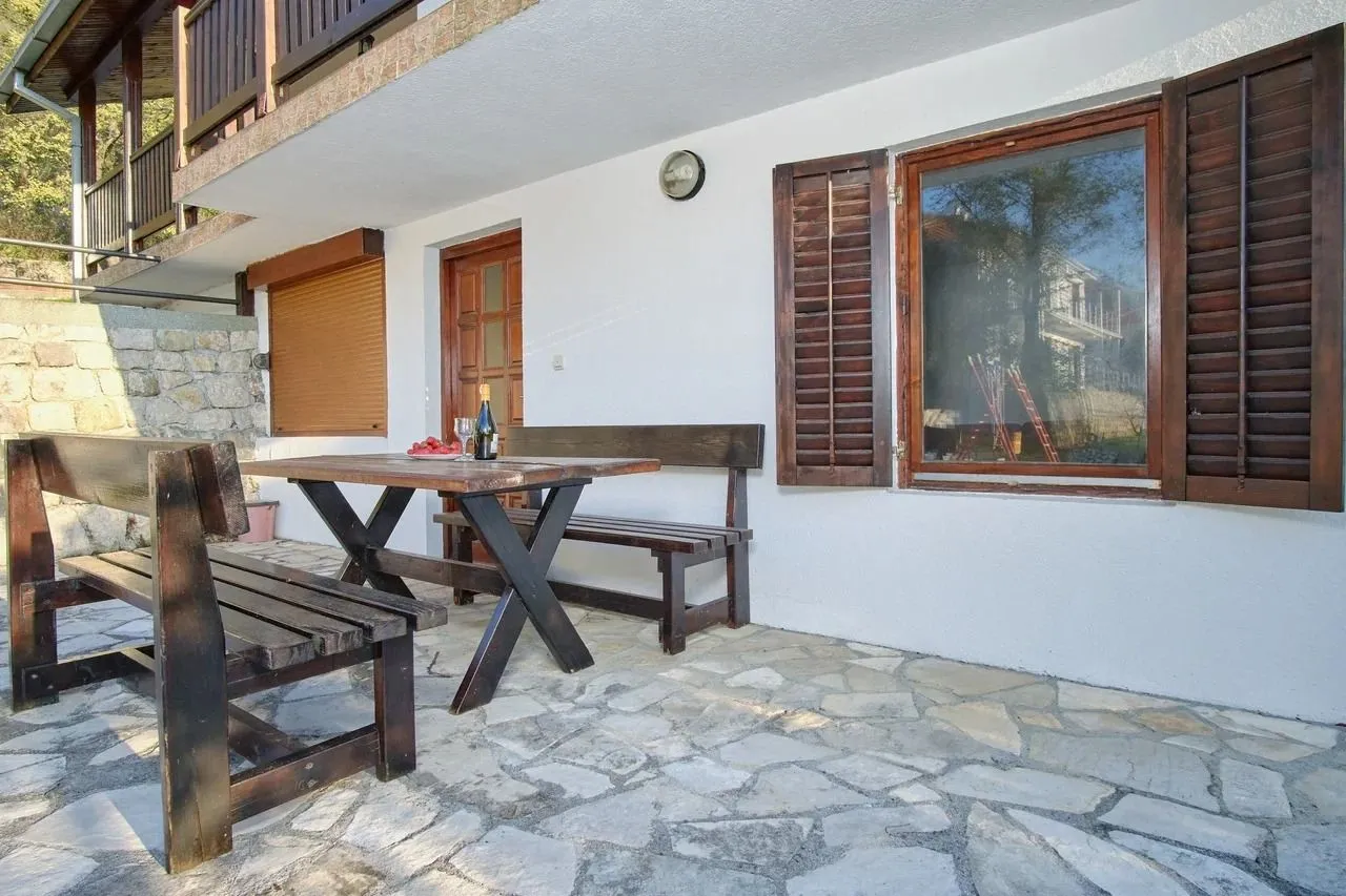 Terrace with a wooden table and benches in front of the house.