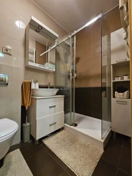 Moderno uređeno kupatilo sa tuš kabinom, umivaonikom i bijelim elementima. - image 14