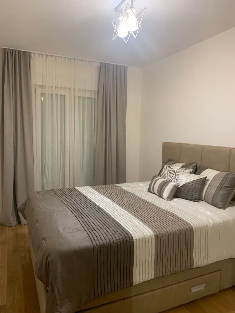 Decorated bedroom with a double bed and a window with curtains.