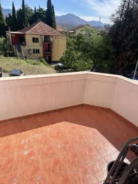 An open terrace tiled with red ceramics, offering a view of the surrounding area and mountains. - image 6