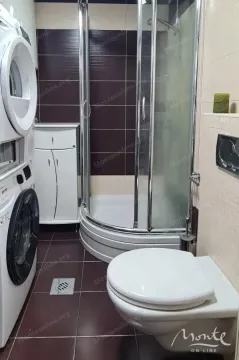 Bathroom with a shower cabin, toilet, and stacked washing and drying machines. - image 5