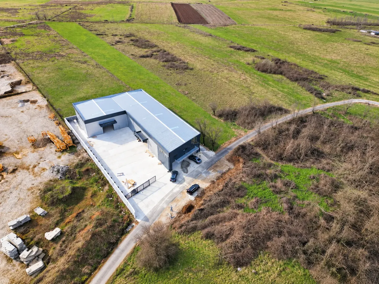 Aerial view of a modern industrial facility with an associated yard and surrounding land.