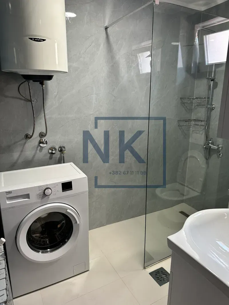 Modern bathroom equipped with a walk-in shower, washing machine, and water heater.