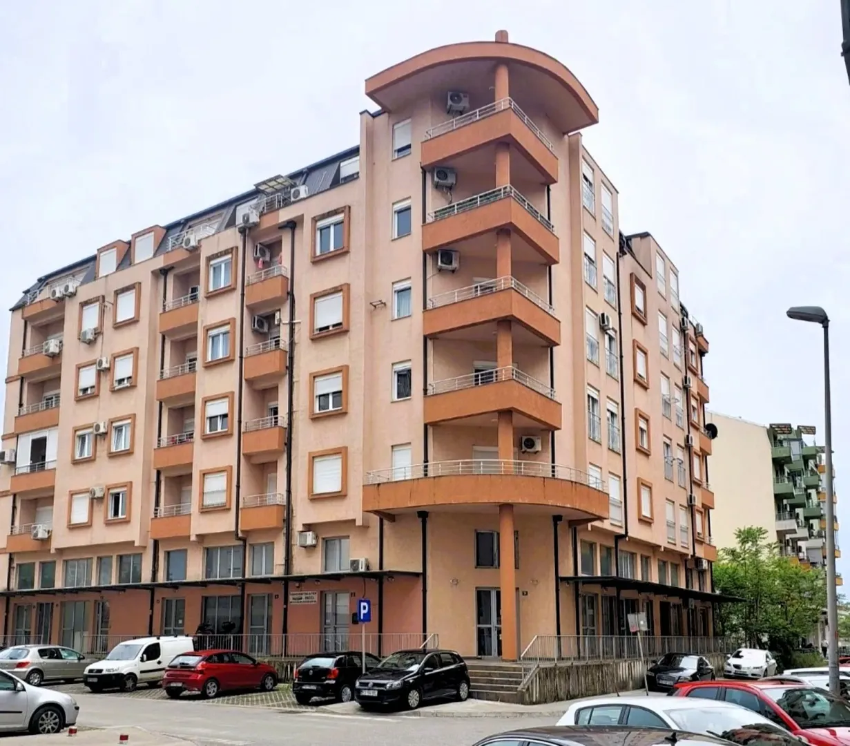 Spoljašnji izgled višespratne stambene zgrade sa terasama i parkingom.