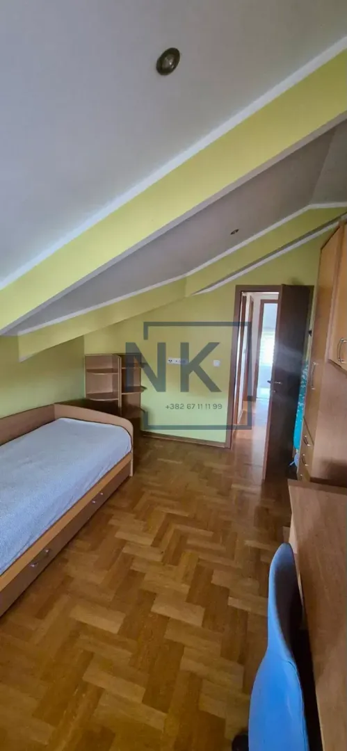 Children's bedroom with a bed, desk, and slanted ceiling.