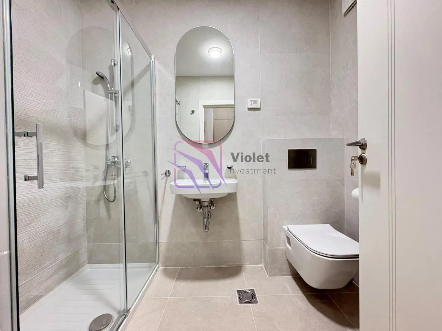 Modernly equipped bathroom with a shower cabin, washbasin, and toilet.
