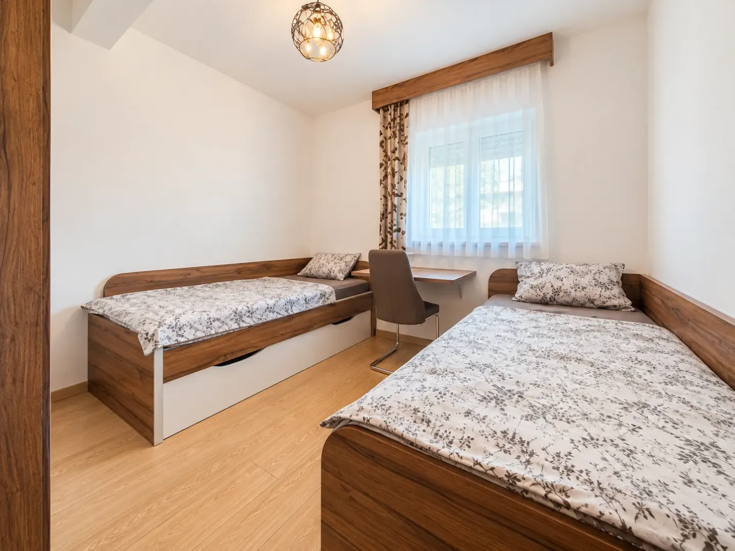 Bedroom with two single beds and a desk under the window.