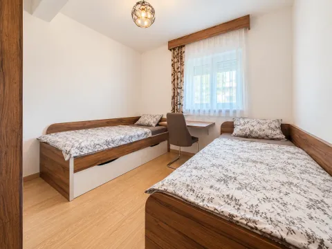 Bedroom with two single beds and a desk under the window. - image 5