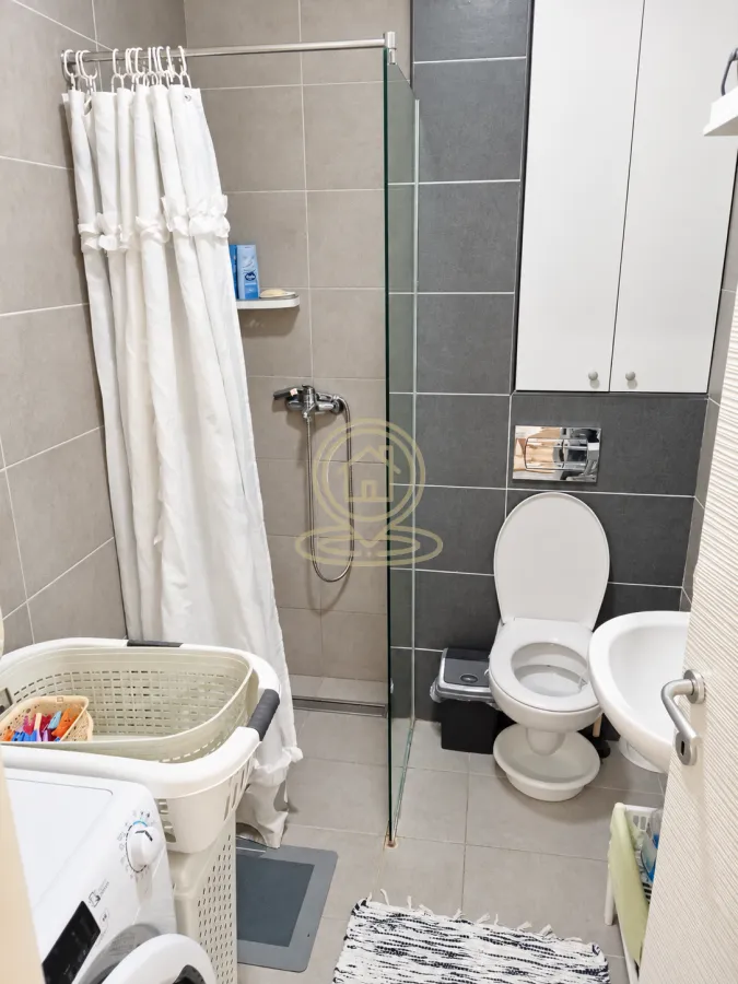 Moderno kupatilo sa tuš kabinom, WC šoljom i umivaonikom.