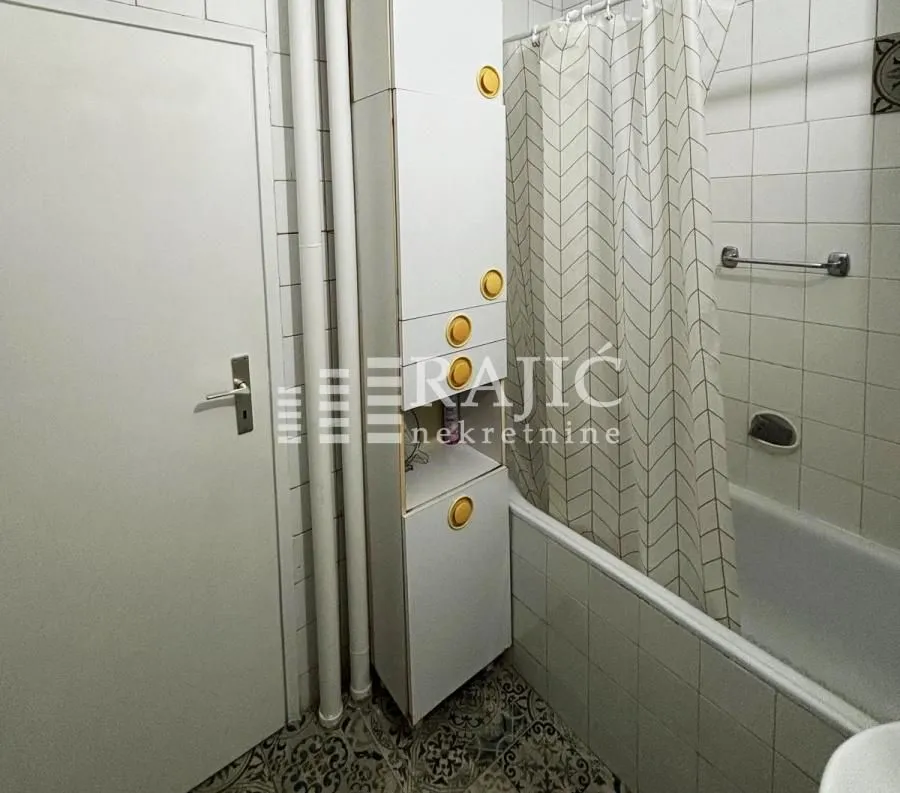 Smaller bathroom with a bathtub and white cabinets.