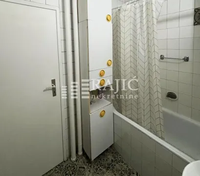 Smaller bathroom with a bathtub and white cabinets. - image 10