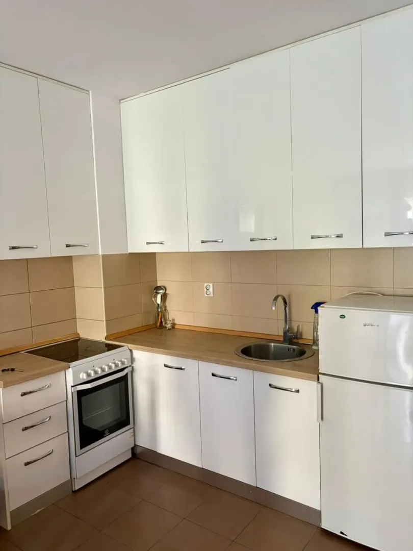 Small kitchen with white cabinets, a stove, and a refrigerator.