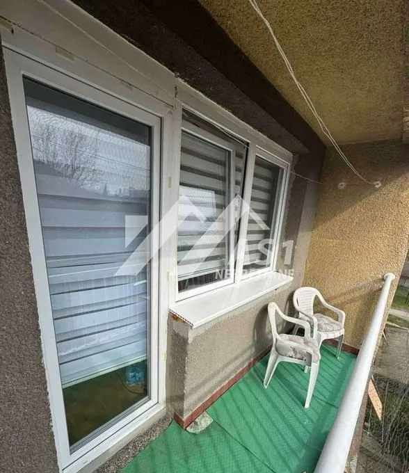 Manji balkon sa prozorima i dve plastične stolice.