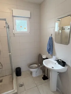 Smaller tiled bathroom with a shower cabin, sink, and toilet. - image 9