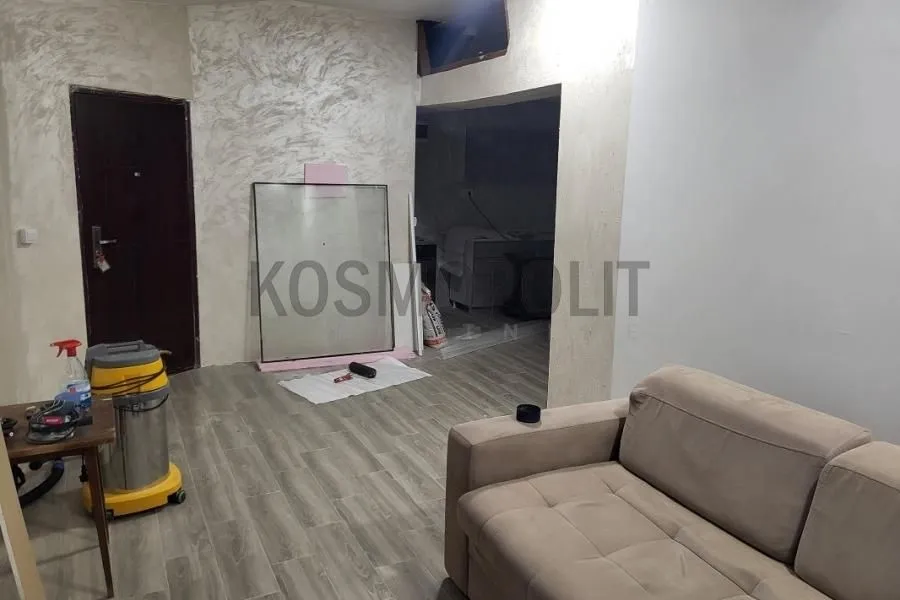 Living room with a sofa and entrance door during renovation.
