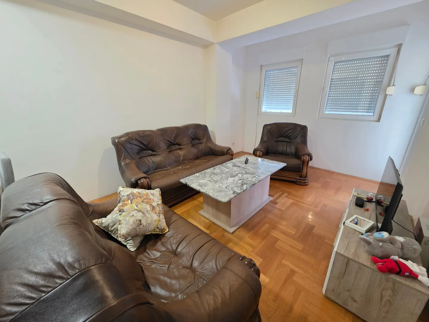 Spacious living room with seating set and parquet flooring.