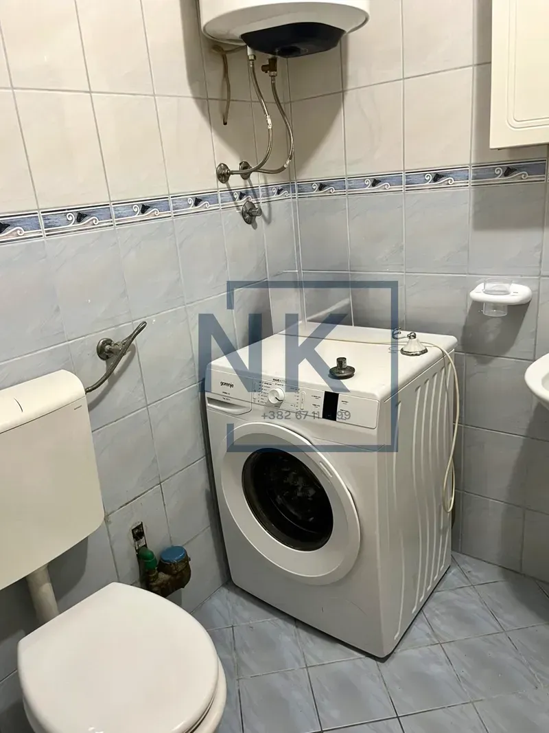 Smaller bathroom with toilet, washing machine and water heater.