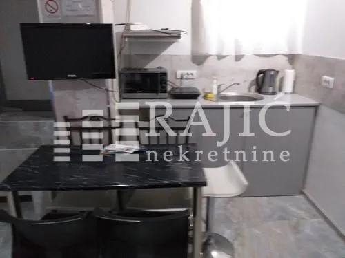 Manja kuhinja sa trpezarijskim stolom i televizorom.