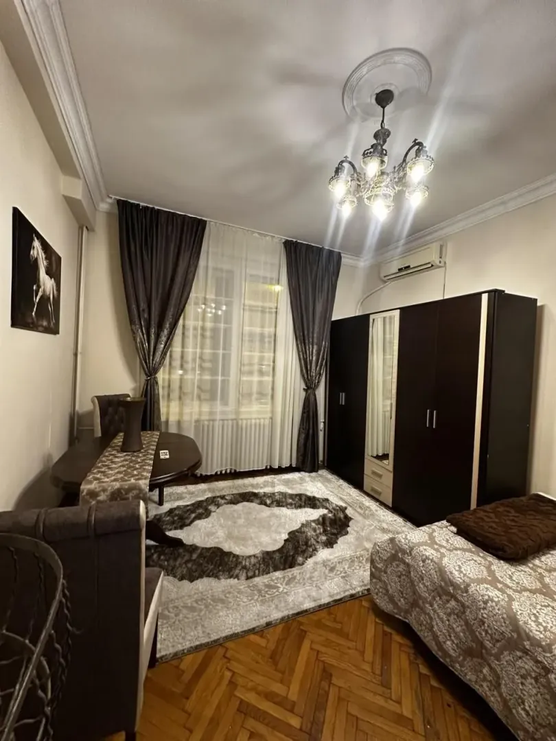 Furnished bedroom with a bed, large wardrobe, and dining table.