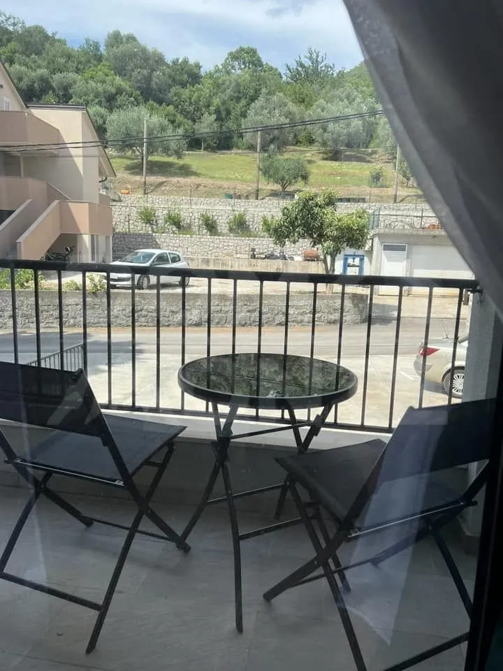 Manji namješten balkon sa stolom i dvije stolice i pogledom na zelenilo.