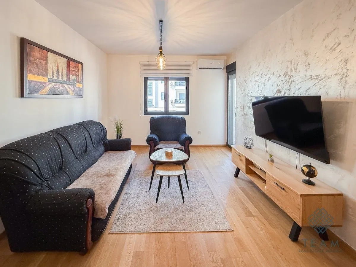 Living room with a sofa set, television, and wooden flooring.