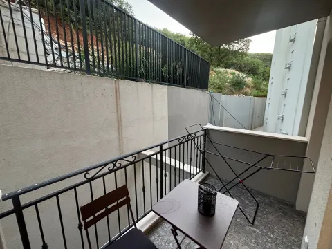 Small balcony with a table, chair, and drying rack. - image 9