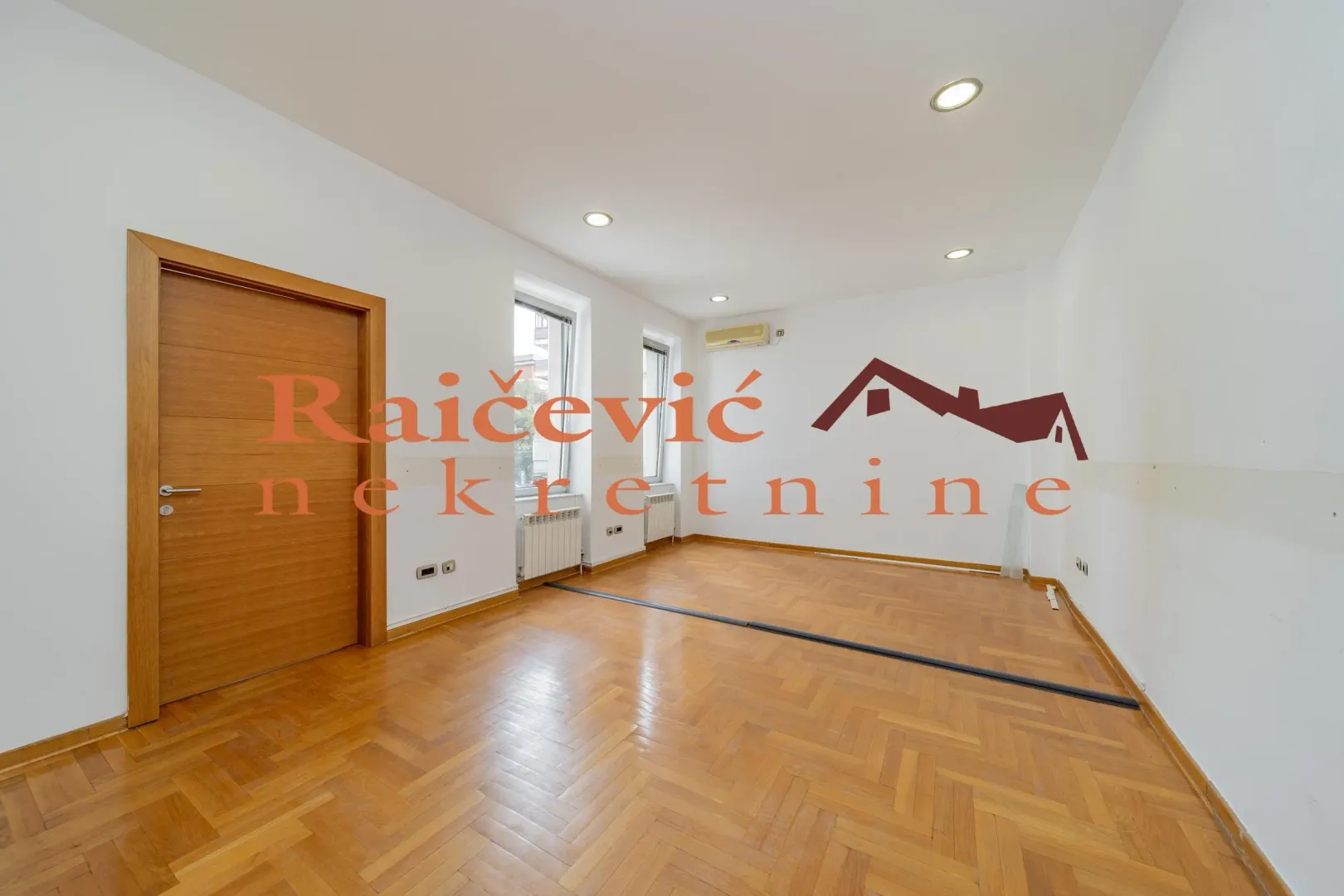 Empty room with parquet flooring and white walls.