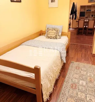 Smaller bedroom with a wooden bed and a view of the dining area. - image 10