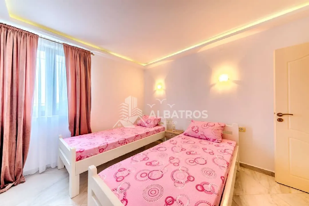 Bedroom with two single beds and a window with pink curtains.