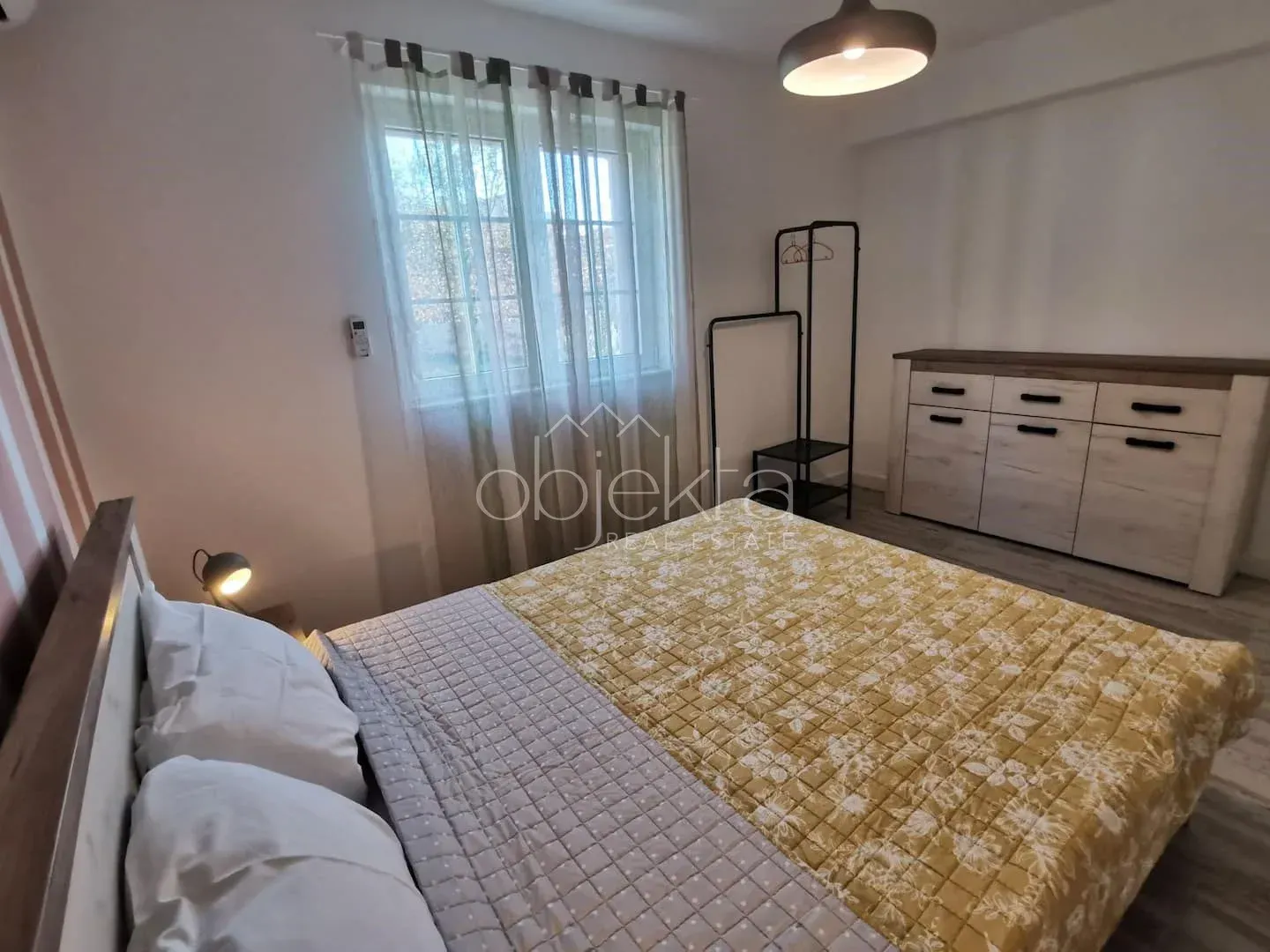 Bedroom with a double bed, window, and dresser.
