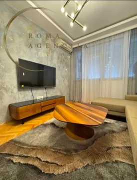 Modern and tidy living room with a sofa, TV, and unique coffee table. - image 3