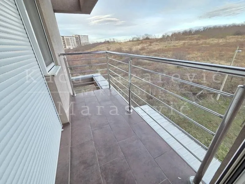Balkon sa metalnom ogradom i popločanim podom.