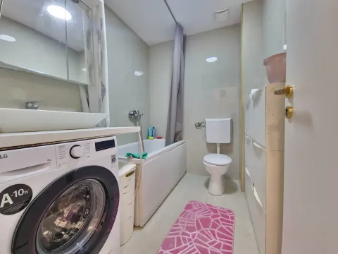 Bathroom equipped with a washbasin, bathtub, toilet, and washing machine. - image 16