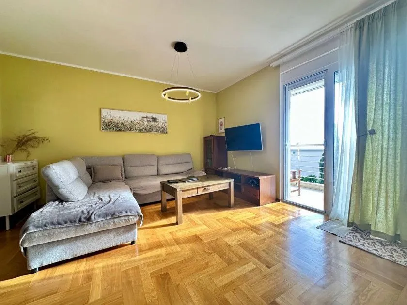 Dnevna soba sa ugaonom garniturom, drvenim stočićem i izlazom na terasu.