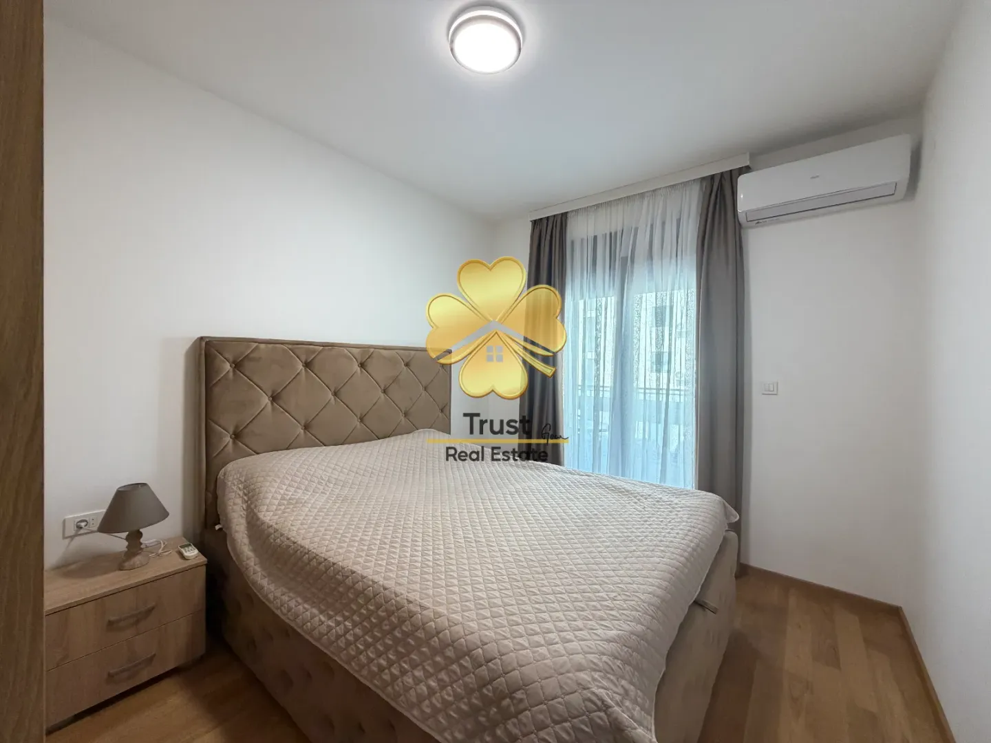 Furnished bedroom with a double bed, nightstand, and air conditioning unit.
