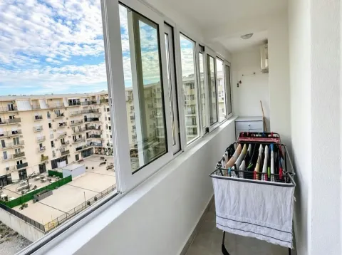 Zastakljeni balkon sa sušačem za veš i pogledom na zgradu. - image 6