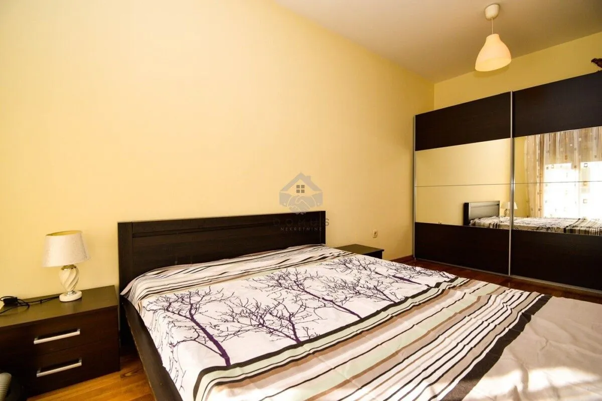 Furnished bedroom with a double bed, bedside tables, and a large wardrobe with a mirror.