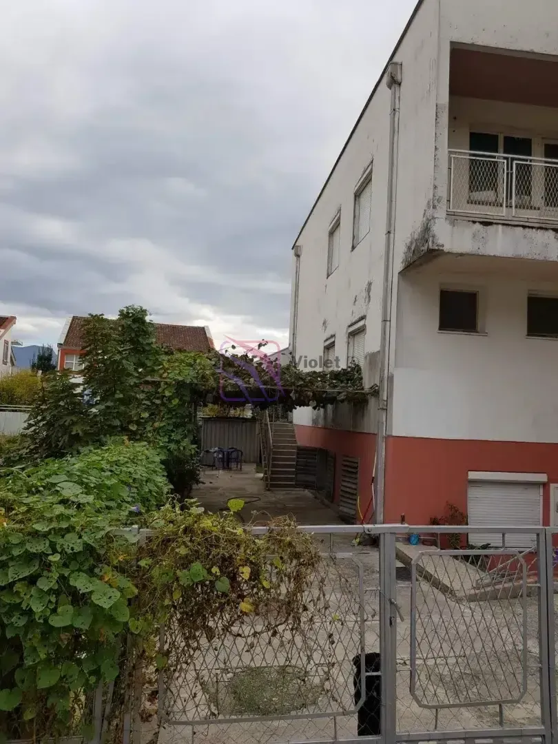 Pogled na dvorište i spoljašnjost kuće sa kapijom i zelenilom.