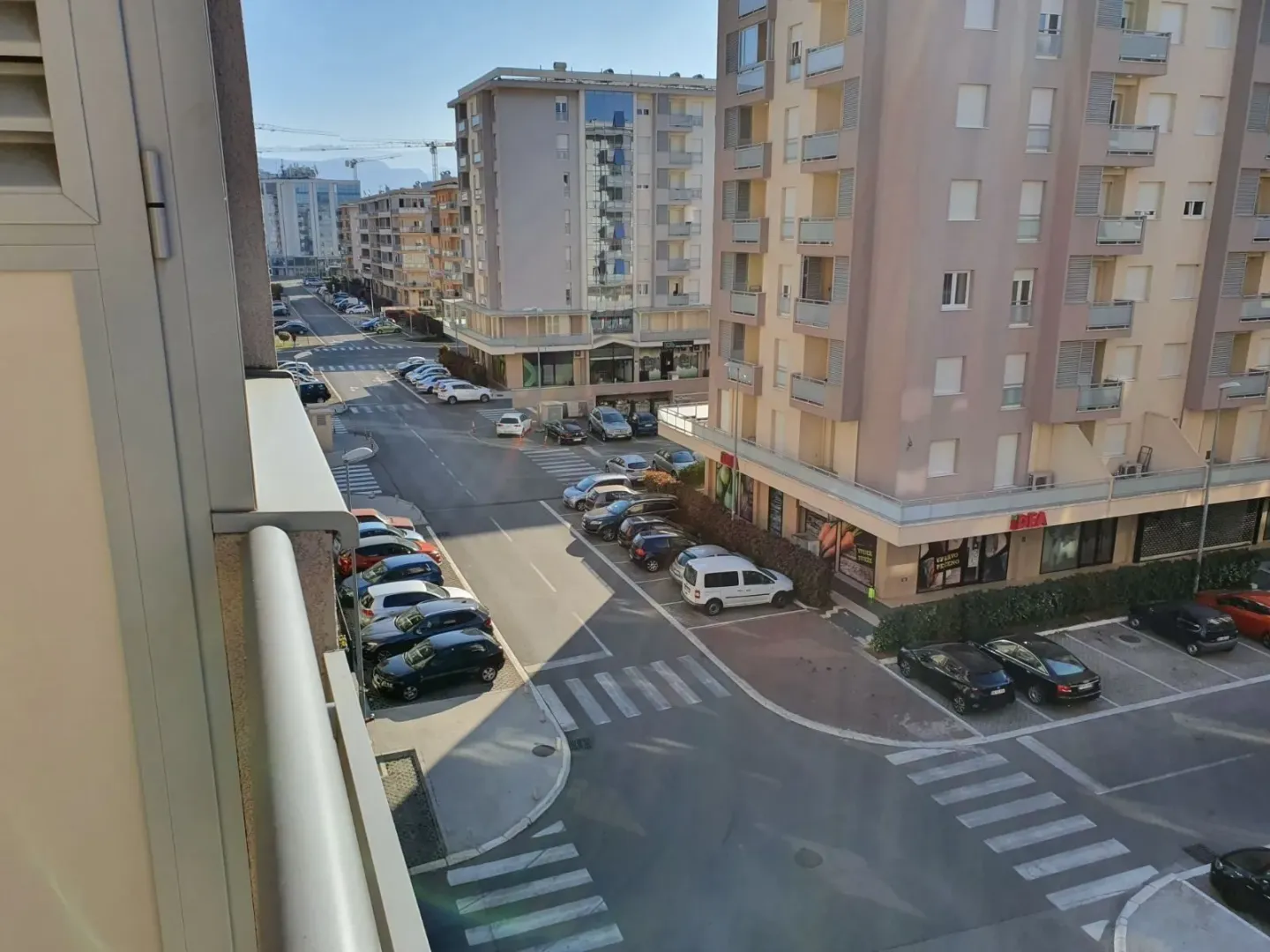 Pogled sa balkona na ulicu i susjedne zgrade.