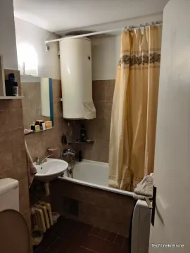 Bathroom with a bathtub, washbasin, and water heater. - image 5