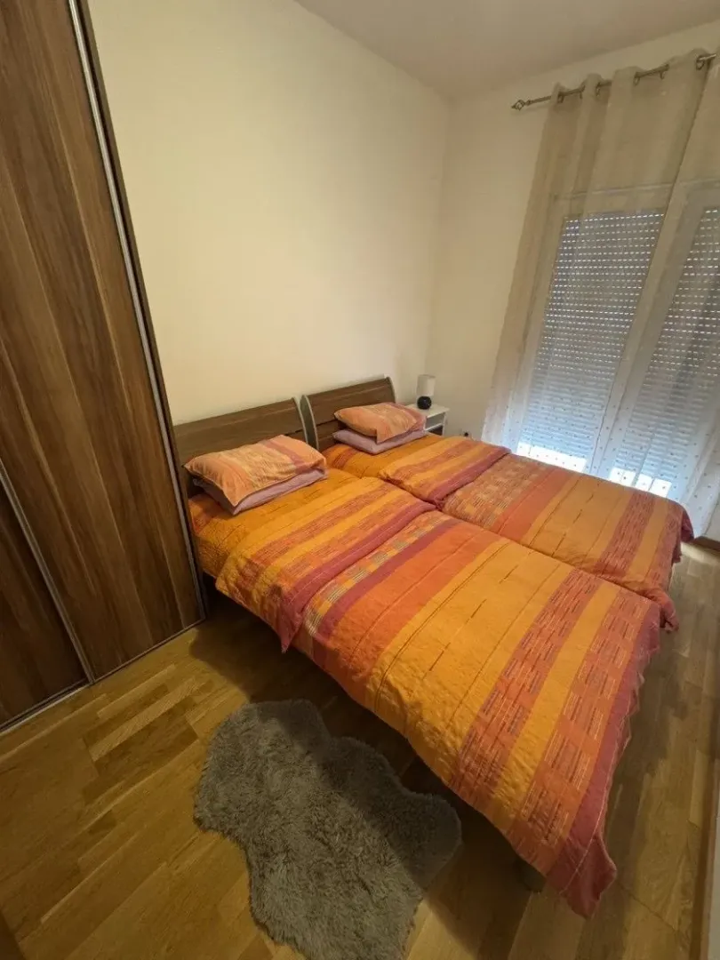 Namještena spavaća soba sa dva kreveta, ormarom i prozorom.