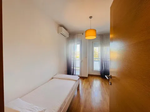 Pogled na urednu spavaću sobu sa krevetom i drvenim podom. - image 6