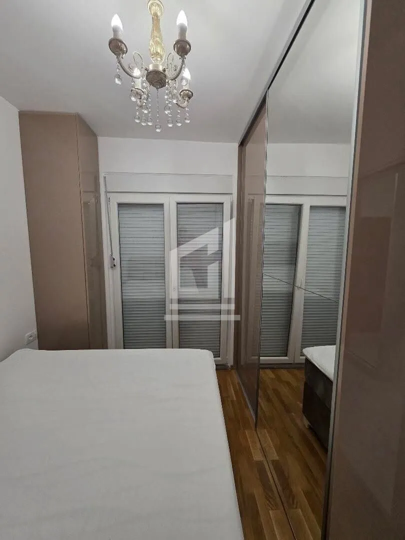 Furnished bedroom with a double bed, large wardrobe, and chandelier.