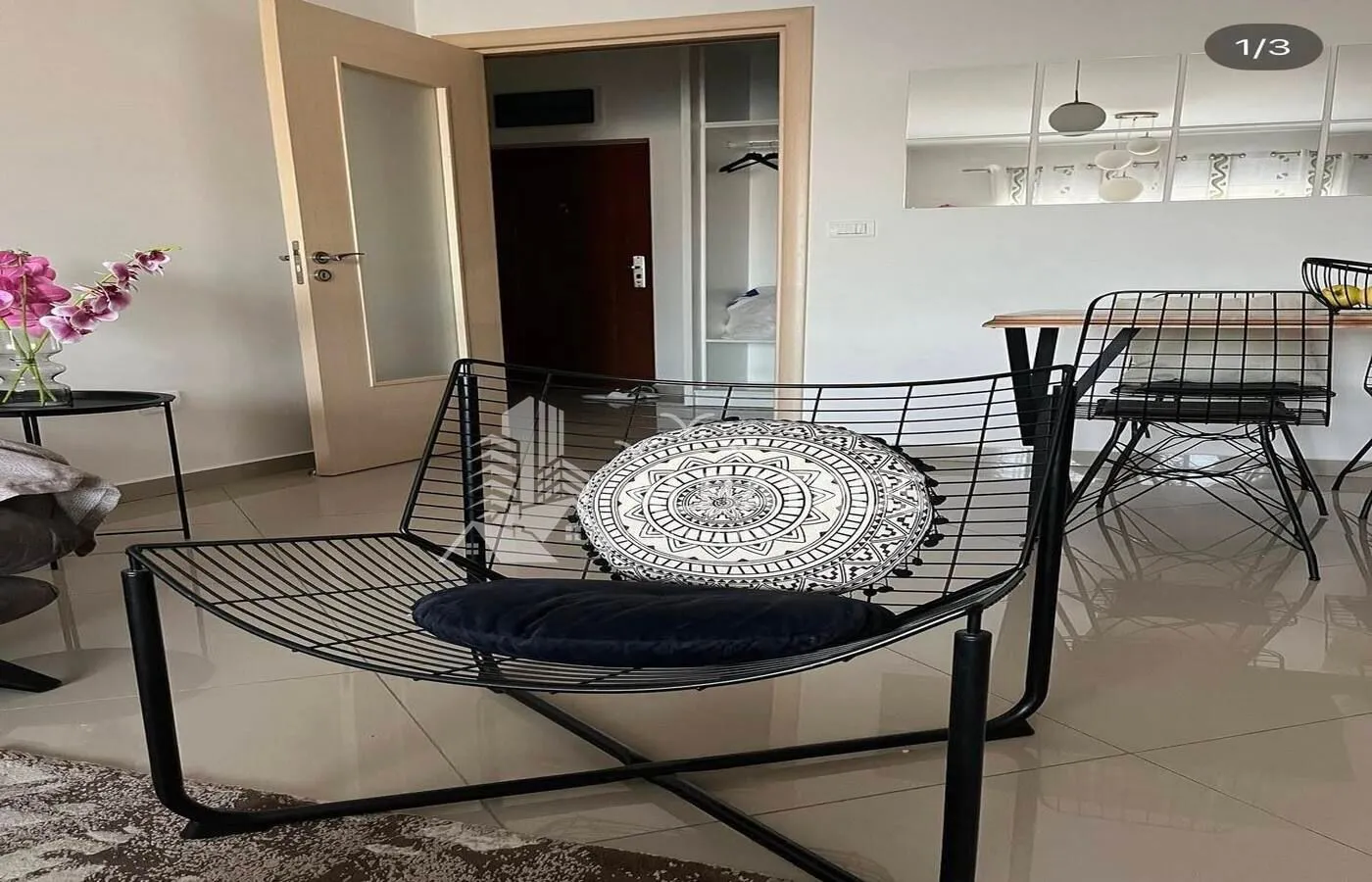Dnevni boravak sa modernom foteljom i trpezarijskim stolom u pozadini.