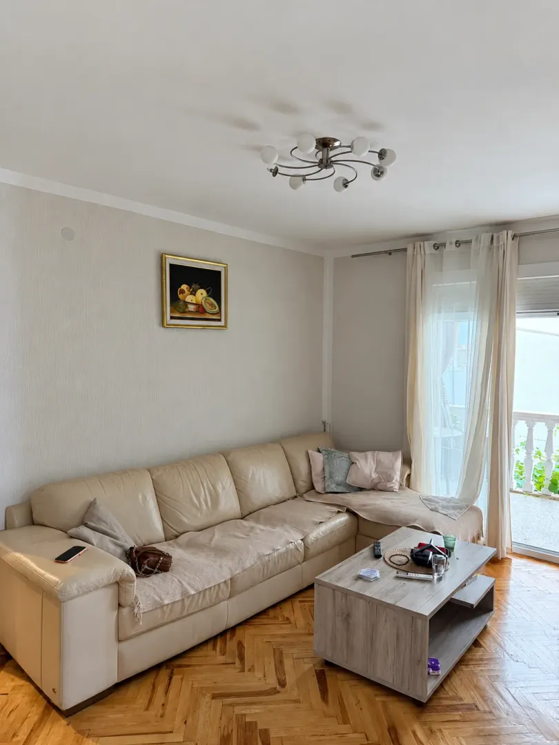 Living room with a sectional sofa, coffee table, and balcony access.