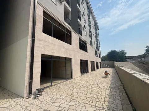 Exterior of a modern residential building with a paved courtyard and ground floor commercial space. - image 2