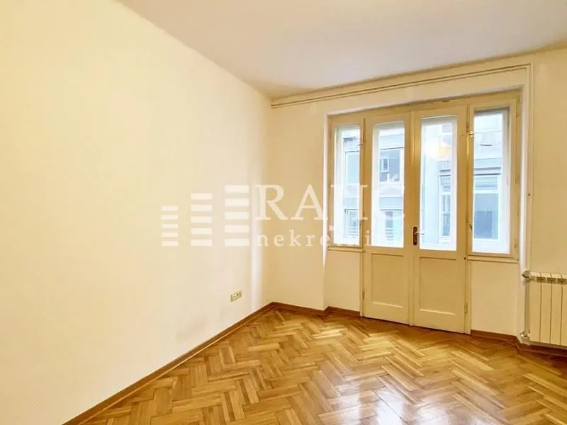 Empty room with wooden parquet flooring and a door leading to the terrace.