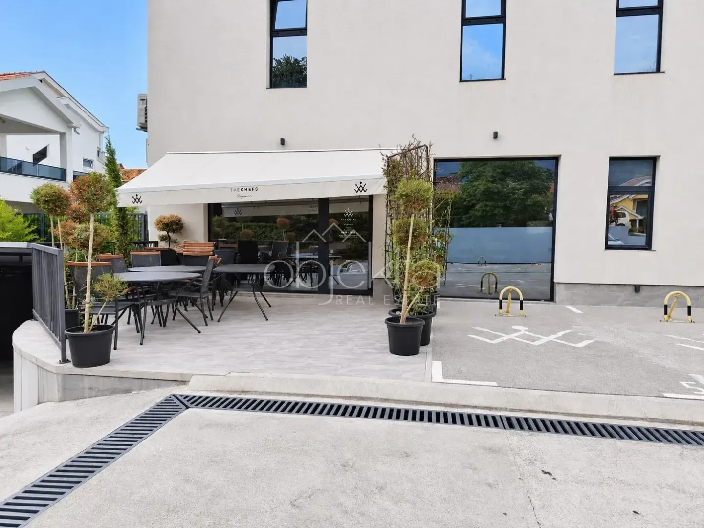 Exterior view of the building with a restaurant terrace and parking space.