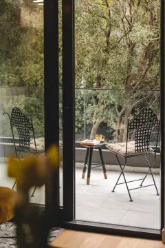 Furnished balcony space with a table and chairs and a view of greenery. - image 10