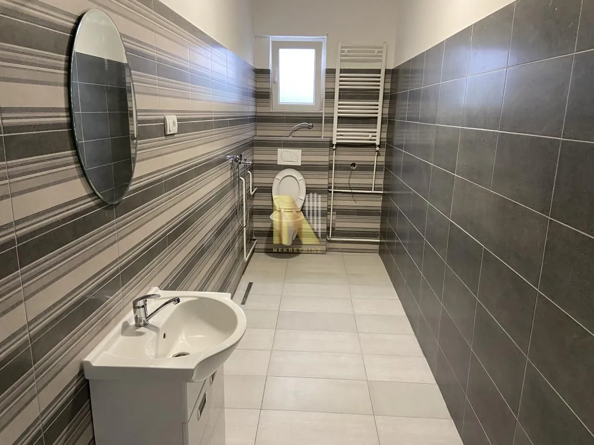 Modern bathroom with a sink, toilet, and tiled walls.